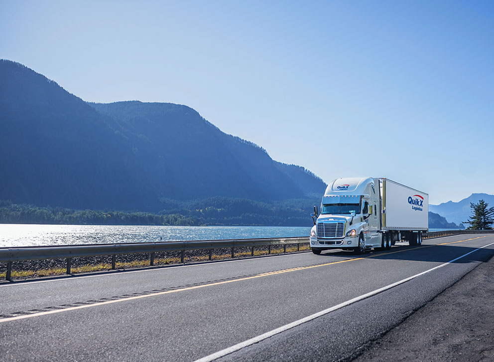 Camion de Quik X Logistics roulant devant un lac canadien